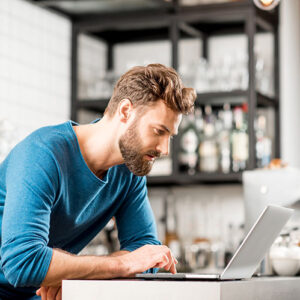 Man working with laptop at the cafe looking for commercial mortgages